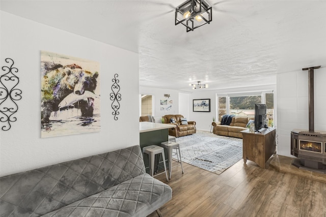 living room featuring hardwood / wood-style flooring, a wood stove, a textured ceiling, and a chandelier