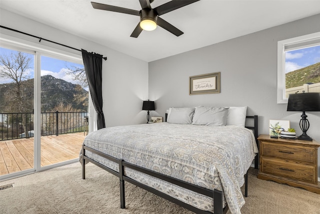 bedroom with ceiling fan, access to exterior, light colored carpet, and multiple windows