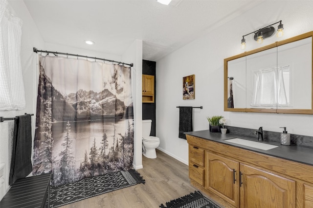 bathroom with hardwood / wood-style floors, vanity, toilet, and walk in shower