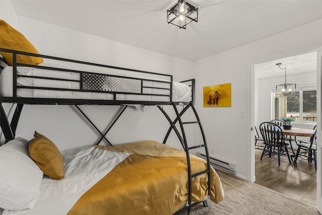 bedroom featuring hardwood / wood-style floors, a notable chandelier, and a baseboard heating unit