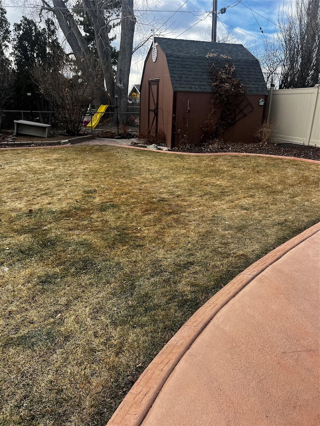 view of yard featuring an outbuilding, a shed, a playground, and fence