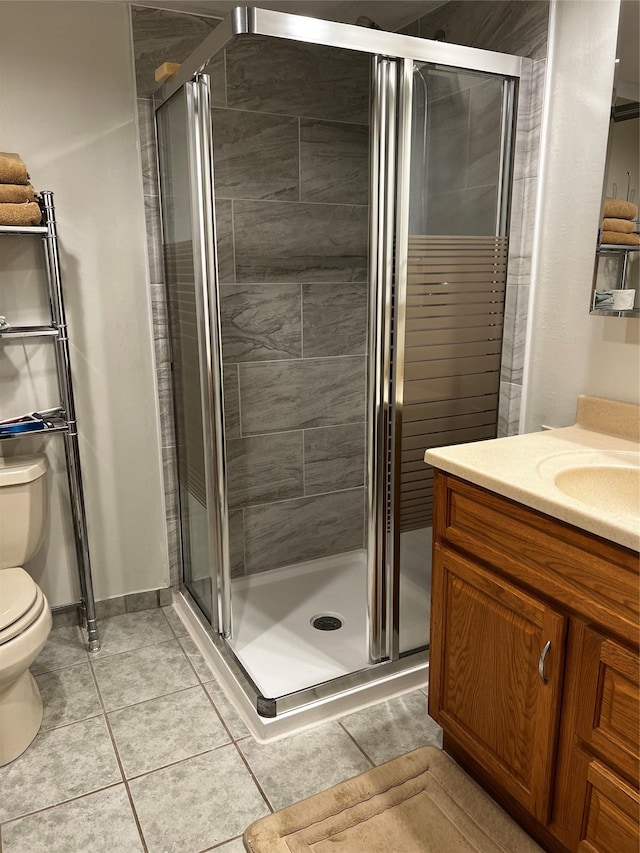 bathroom with baseboards, toilet, tile patterned flooring, vanity, and a shower stall