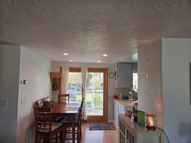 dining space with a textured ceiling, recessed lighting, and light wood-style floors