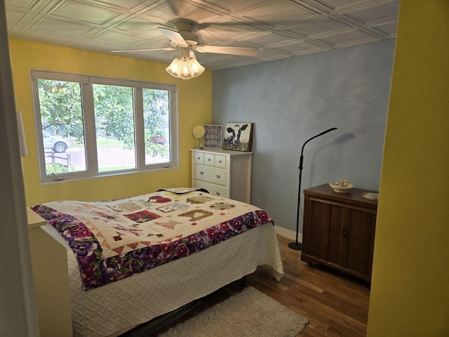 bedroom featuring an ornate ceiling, baseboards, ceiling fan, and wood finished floors