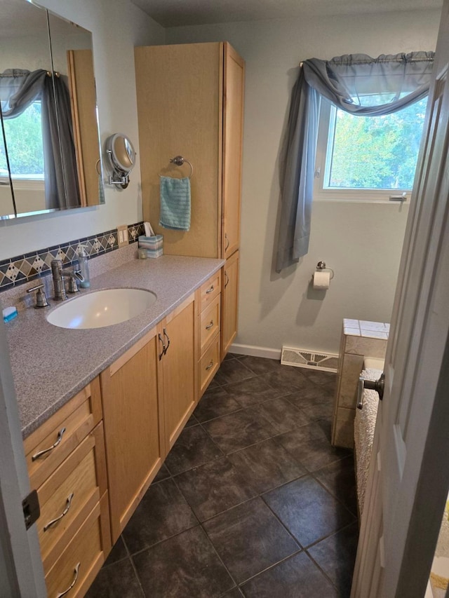 bathroom featuring baseboards, vanity, visible vents, and decorative backsplash