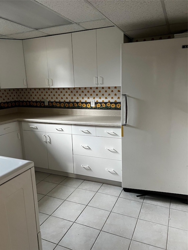 kitchen featuring a paneled ceiling, range, and freestanding refrigerator