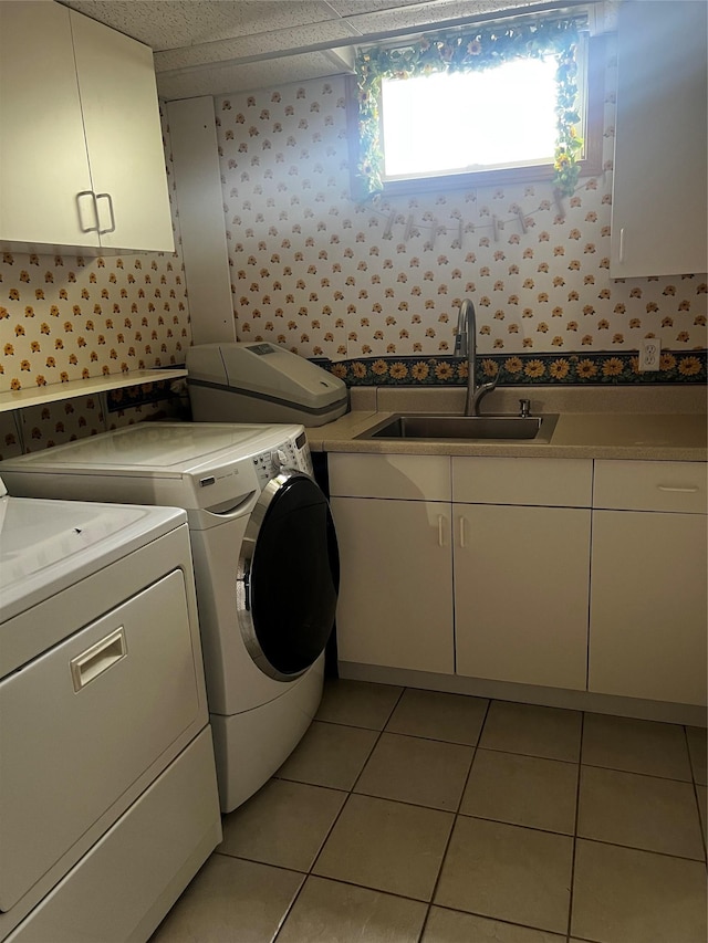 washroom featuring light tile patterned floors, cabinet space, a sink, washer and dryer, and wallpapered walls