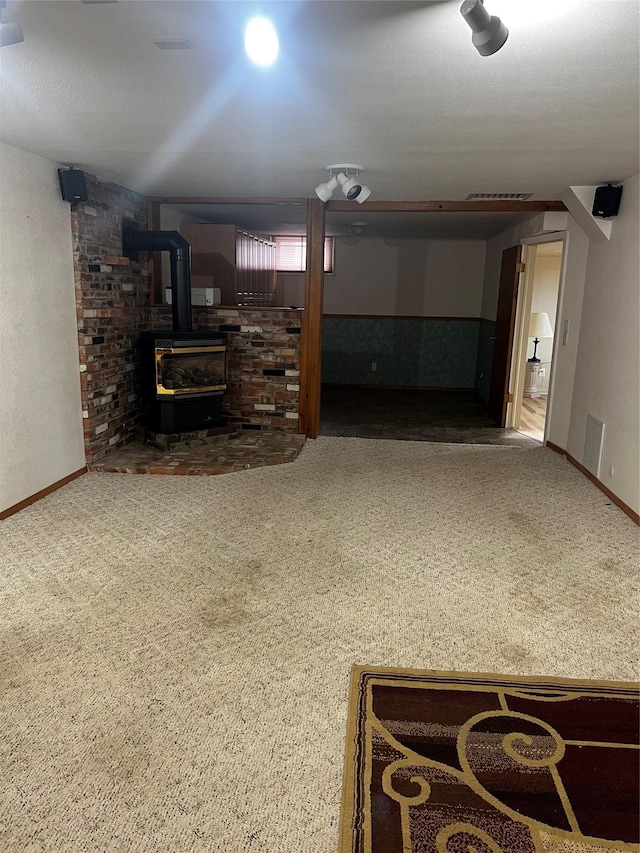 living area with visible vents, carpet flooring, and a wood stove