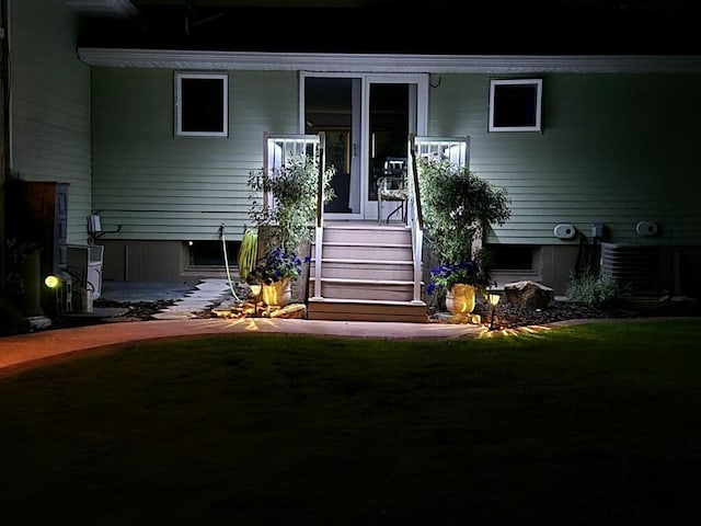 entrance to property with central air condition unit and a lawn