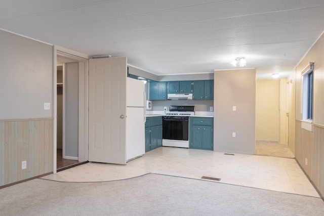 kitchen with blue cabinetry, white appliances, light colored carpet, and wood walls