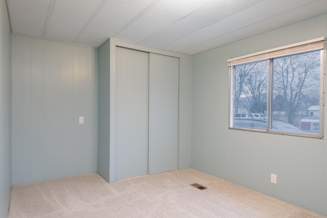 unfurnished bedroom featuring light carpet and a closet