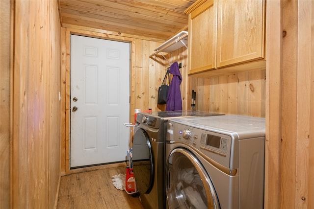 washroom featuring cabinets, light wood-type flooring, wood ceiling, wooden walls, and separate washer and dryer