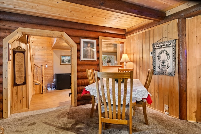 carpeted dining space featuring wooden walls, beamed ceiling, and wood ceiling