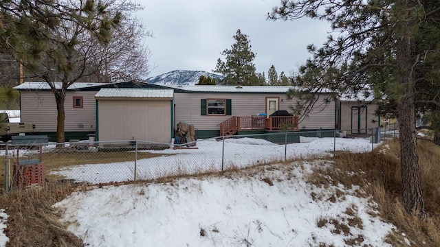 view of front of property with a deck with mountain view, fence, and metal roof