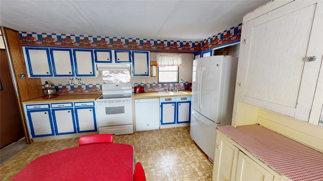 kitchen featuring white appliances, a sink, under cabinet range hood, and light floors