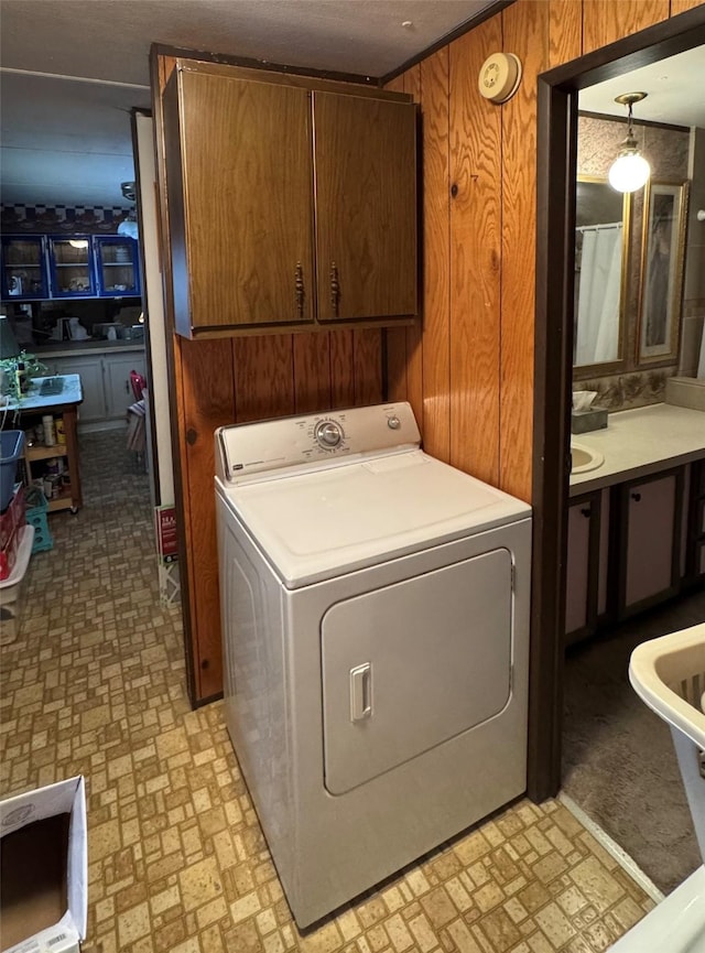 laundry area with cabinets, washer / dryer, and wooden walls