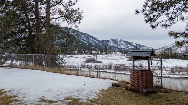 yard covered in snow featuring a mountain view and fence