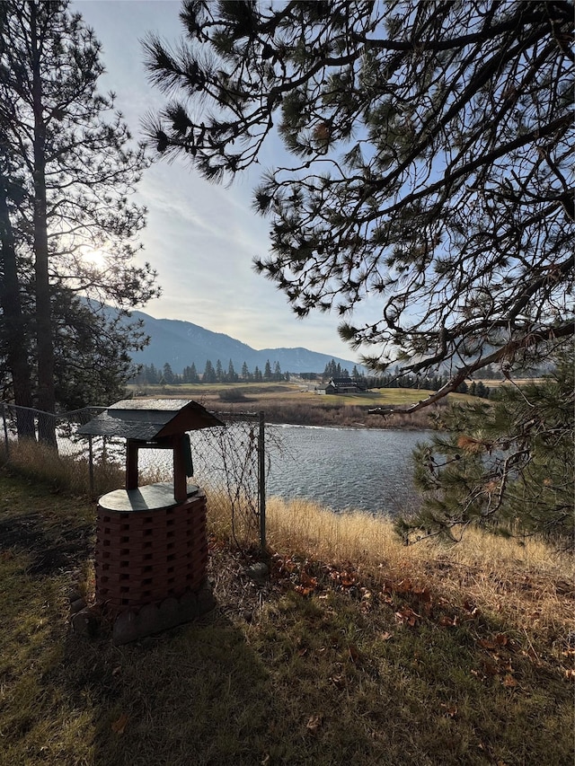 property view of water featuring a mountain view and fence