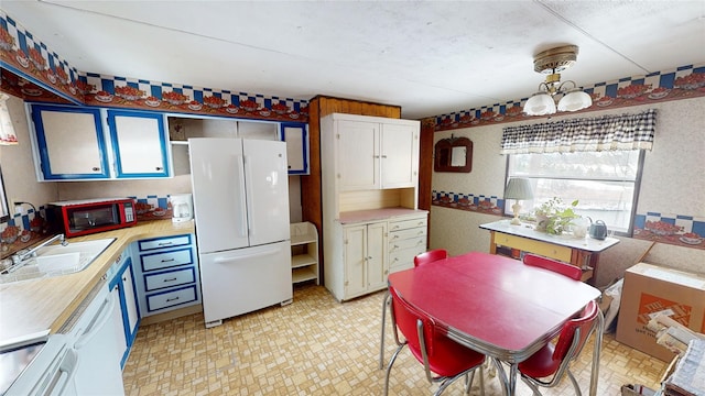 kitchen with a notable chandelier, a sink, light countertops, range, and freestanding refrigerator