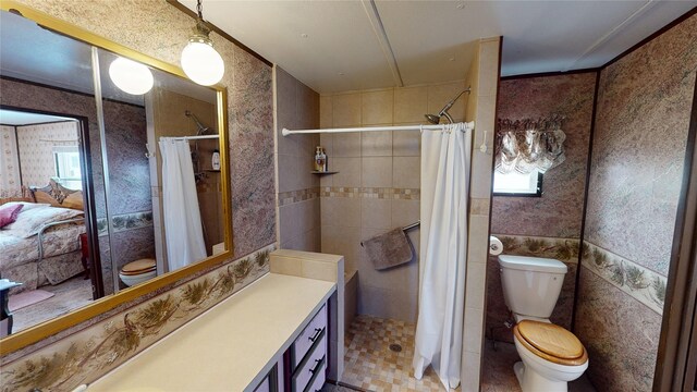 bathroom with ensuite bathroom, tiled shower, toilet, and wallpapered walls