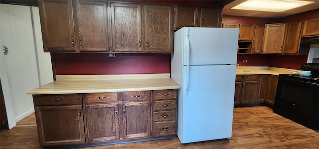 kitchen featuring white refrigerator, sink, light hardwood / wood-style flooring, and black / electric stove