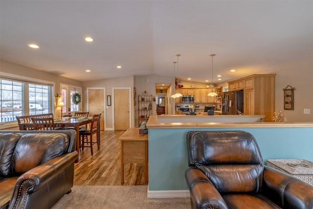 kitchen with decorative light fixtures, a kitchen island, stainless steel appliances, and vaulted ceiling