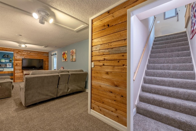 living room featuring carpet, a textured ceiling, and wooden walls