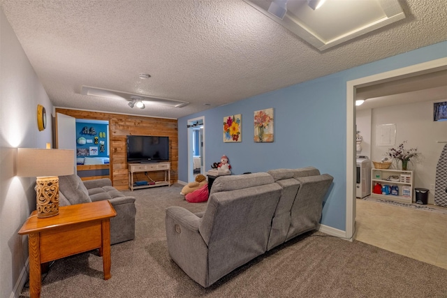 living room featuring wood walls, carpet floors, a textured ceiling, and washer / dryer