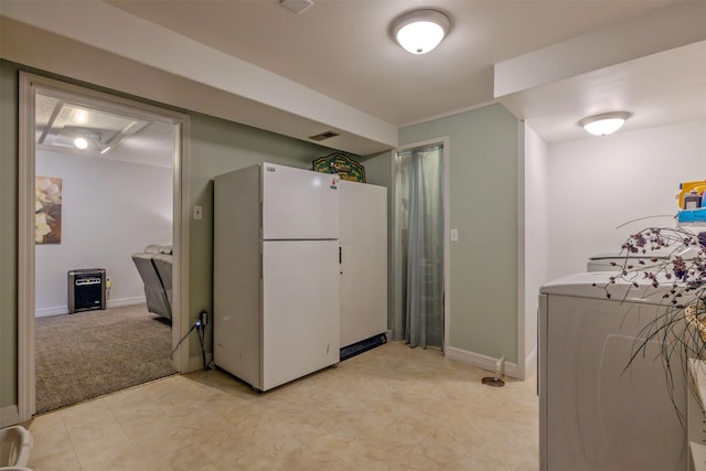 kitchen with washer / clothes dryer, light carpet, and white fridge