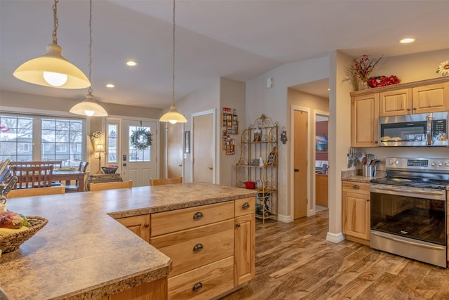 kitchen featuring light brown cabinets, decorative light fixtures, and appliances with stainless steel finishes