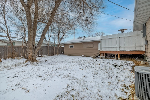 snowy yard featuring a wooden deck and cooling unit