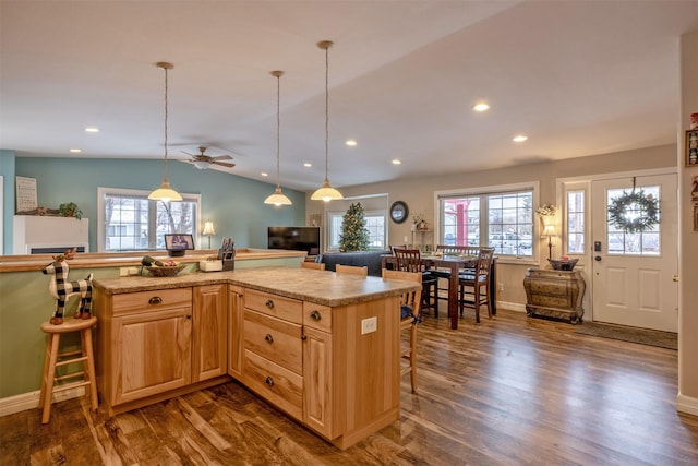 kitchen with a breakfast bar area, a kitchen island, dark hardwood / wood-style floors, and lofted ceiling