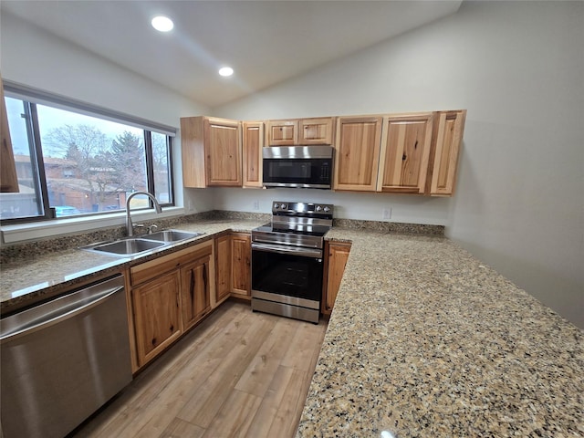 kitchen featuring light wood-type flooring, light stone counters, stainless steel appliances, sink, and lofted ceiling