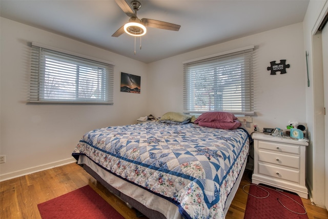 bedroom with ceiling fan, dark hardwood / wood-style flooring, and multiple windows