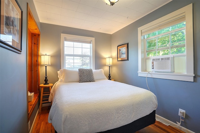 bedroom with dark hardwood / wood-style floors, cooling unit, and ornamental molding