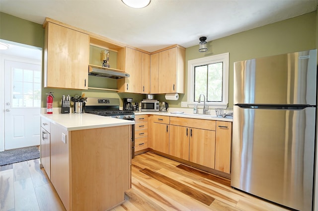 kitchen featuring light brown cabinets, range hood, kitchen peninsula, appliances with stainless steel finishes, and light wood-type flooring