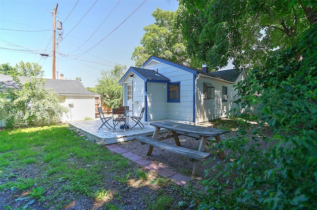 back of property with a deck and a lawn