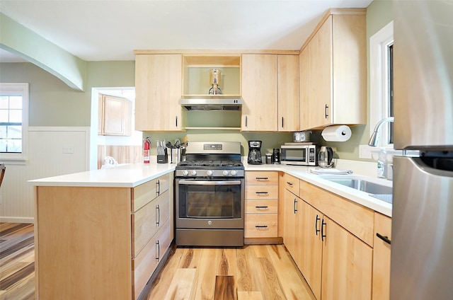 kitchen with kitchen peninsula, light brown cabinetry, light wood-type flooring, stainless steel appliances, and ventilation hood