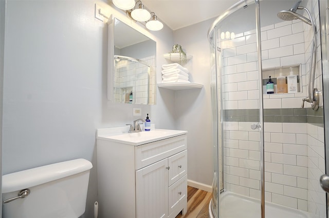 bathroom featuring wood-type flooring, vanity, toilet, and a shower with door