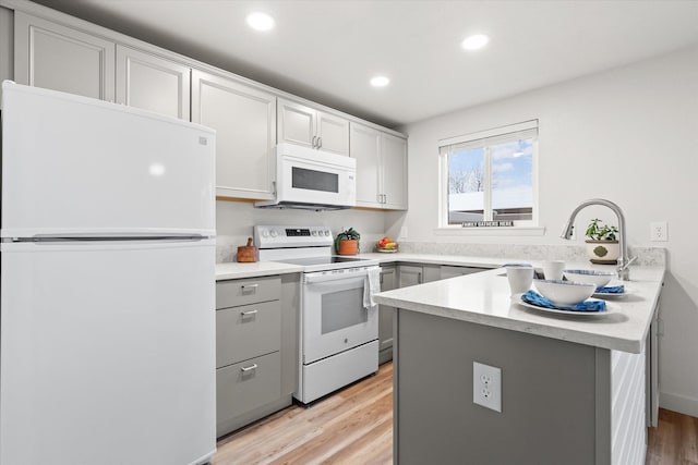 kitchen with white appliances, sink, light hardwood / wood-style flooring, gray cabinets, and kitchen peninsula