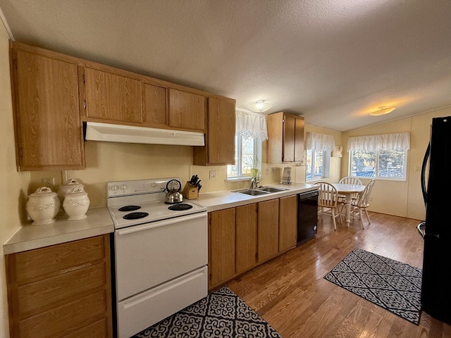 kitchen featuring a textured ceiling, vaulted ceiling, sink, black appliances, and light hardwood / wood-style floors