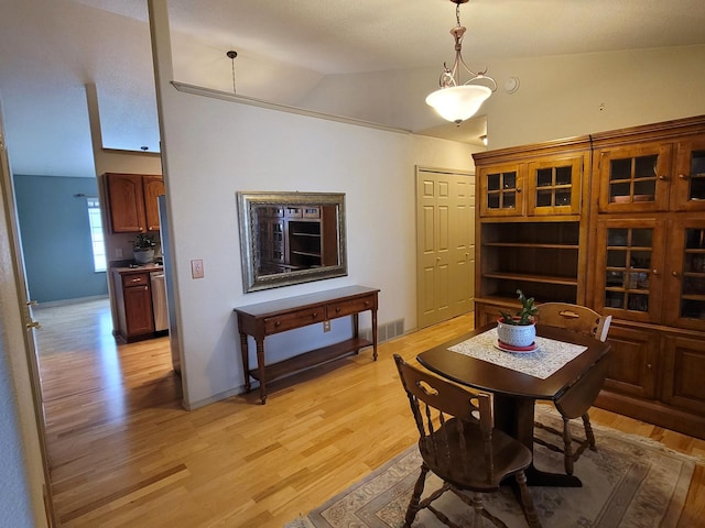 dining area with light wood-type flooring and lofted ceiling