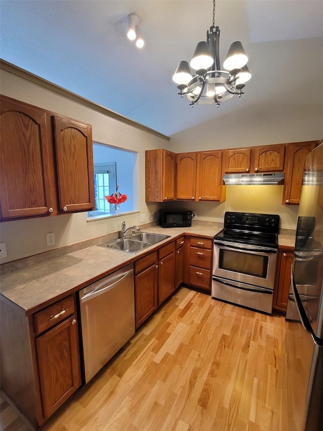 kitchen with pendant lighting, lofted ceiling, light wood-type flooring, a notable chandelier, and stainless steel appliances