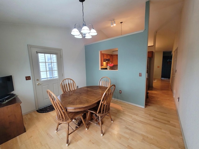 dining space with light wood-type flooring, vaulted ceiling, and a notable chandelier