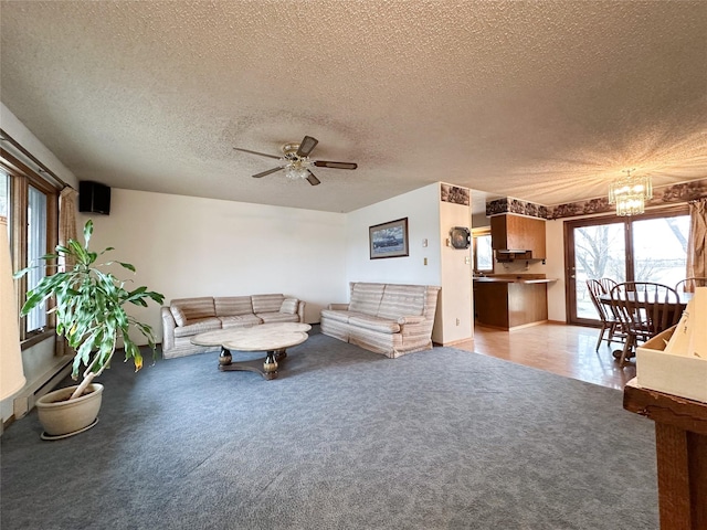 living room with ceiling fan with notable chandelier, light colored carpet, and a textured ceiling