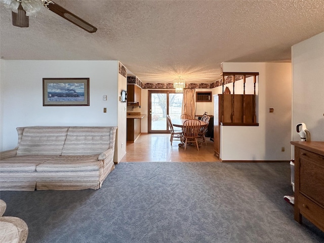 carpeted living room featuring ceiling fan and a textured ceiling