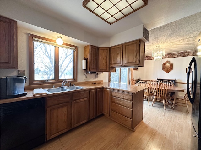 kitchen featuring kitchen peninsula, sink, light hardwood / wood-style flooring, dishwasher, and a chandelier