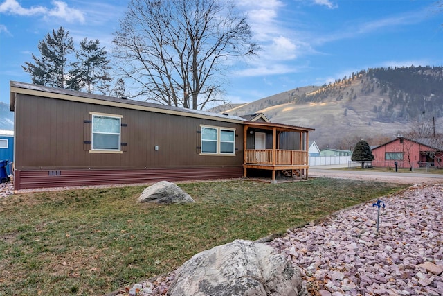 back of property with a mountain view and a yard