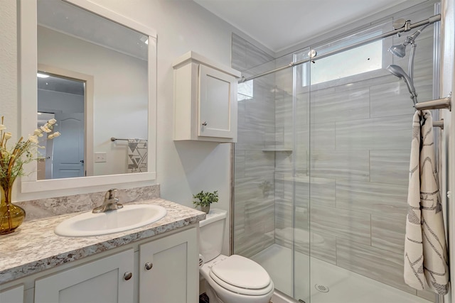 bathroom featuring a shower with door, vanity, and toilet