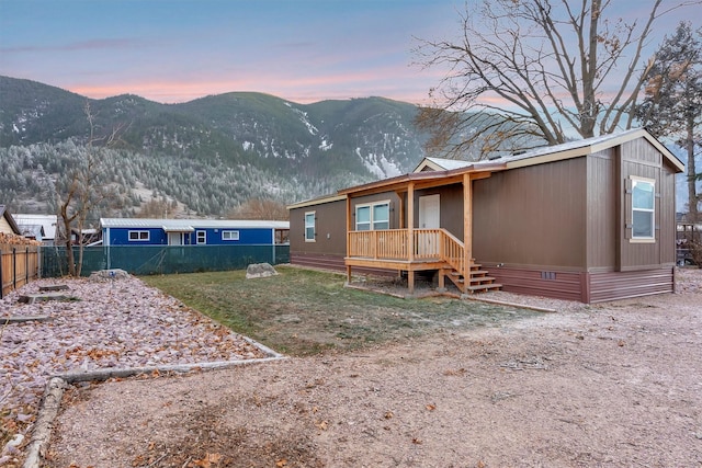 back house at dusk with a deck with mountain view